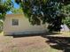 View of backyard, partially shaded by a tree, showing the back side of the house at 5211 Jersey S Ave, Gulfport, FL 33707