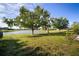 Expansive backyard with lush green grass and mature trees, with serene lake views at 5460 Sandy Shell Dr, Apollo Beach, FL 33572