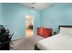 A blue bedroom with carpeting with a red dresser visible in the adjacent room at 5460 Sandy Shell Dr, Apollo Beach, FL 33572