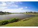 Scenic lake view with lush green lawns and surrounding houses under a partly cloudy sky at 5460 Sandy Shell Dr, Apollo Beach, FL 33572