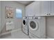 Functional laundry room with modern washer and dryer, utility sink, and ample cabinet storage at 606 Winterside Dr, Apollo Beach, FL 33572