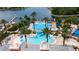 Aerial view of community pool with palm trees, waterslide and lounge chairs overlooking lake and boat dock at 606 Winterside Dr, Apollo Beach, FL 33572