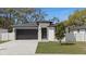 Charming front exterior featuring a modern black trimmed windows and a black garage door at 6302 N 39Th St, Tampa, FL 33610