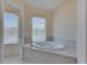Relaxing bathroom with a large soaking tub, tiled surround, and natural light from the window at 6317 Marbella Blvd, Apollo Beach, FL 33572