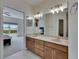 Vanity in bath with dual sinks, marble countertop, and views to main bedroom at 6317 Marbella Blvd, Apollo Beach, FL 33572