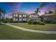 Twilight image of a luxury home featuring manicured landscaping and a paver driveway at 6317 Marbella Blvd, Apollo Beach, FL 33572