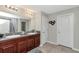 Modern bathroom with double vanity, granite countertops, wood cabinets and a large mirror with decorative lighting at 7019 Wiseman Run Dr, Sun City Center, FL 33573