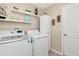 Bright laundry area with floating shelves above the washer and dryer for storage and organization at 7019 Wiseman Run Dr, Sun City Center, FL 33573