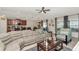 Open-concept living room with a large sectional sofa, ceiling fan, and seamless flow to the dining and kitchen at 7019 Wiseman Run Dr, Sun City Center, FL 33573