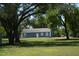 Exterior view of home featuring a spacious lawn and mature shade trees at 7040 Lumberton Rd, Zephyrhills, FL 33540