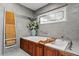 Soaking tub in a modern bathroom with a wood-trimmed base and stylish fixtures at 720 Brightwaters Ne Blvd, St Petersburg, FL 33704