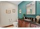Stylish powder room featuring dark wood vanity, granite countertop, and elegant teal accent wall at 720 Brightwaters Ne Blvd, St Petersburg, FL 33704