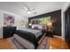 Bedroom with a stylish accent wall, comfortable bed, ceiling fan and beautiful hardwood floors at 7909 Garden N Dr, St Petersburg, FL 33710