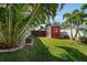 Exterior view of a red shed surrounded by greenery and palm trees at 7909 Garden N Dr, St Petersburg, FL 33710