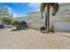 Townhome exterior showcasing brick paved driveways, garages, and lush tropical landscaping, enhanced by a clear blue sky at 830 Pinellas Bayway S, St Petersburg, FL 33715