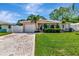 Attractive single-story house featuring a green lawn, palm trees, and a paved driveway to the garage at 940 43Rd Ne Ave, St Petersburg, FL 33703