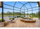 A screened patio overlooking a serene lake features a stone hot tub and comfortable seating, enhancing outdoor living at 9897 Sago Point Dr, Seminole, FL 33777
