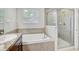 Well-lit bathroom featuring a tub and separate glass-enclosed shower at 10524 White Peacock Pl, Riverview, FL 33578
