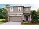 Inviting two-story home featuring a stone facade, attached two-car garage, and manicured landscaping at 10604 Dusty Boot Rd, Land O Lakes, FL 34638