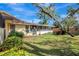 Landscaped yard showcasing the back of the home with a screened porch and patio area at 107 Parkside Colony Dr, Tarpon Springs, FL 34689