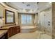 Luxurious bathroom with a soaking tub, walk-in shower with glass door, and vanity with wooden cabinets at 109 Wateredge Ct, Safety Harbor, FL 34695