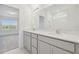Bathroom featuring double vanity sinks, a large mirror and tiled shower, filled with natural light at 11022 Moonsail Dr, Parrish, FL 34219