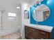 Clean bathroom featuring a modern vanity, round mirror, and a shower tub combo with a bright window at 11368 93Rd St, Largo, FL 33773