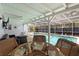 Covered patio with outdoor furniture overlooks a sparkling pool, perfect for outdoor relaxation and entertaining at 11368 93Rd St, Largo, FL 33773