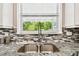 Modern kitchen sink featuring granite countertops and mosaic tile backsplash with a view to the outdoors at 12525 Sparkleberry Rd, Tampa, FL 33626