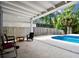 Covered patio with comfortable seating next to a swimming pool and lush landscaping at 12525 Sparkleberry Rd, Tampa, FL 33626