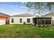 View of the exterior of the home and the screened-in patio and a well-kept green lawn at 1318 Crimson Clover Ln, Wesley Chapel, FL 33543