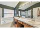 This bathroom features a dual sink vanity with soaking tub beneath a frosted window for privacy at 1318 Crimson Clover Ln, Wesley Chapel, FL 33543