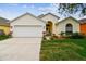 Charming single-story home with a well-manicured lawn, a two-car garage, and beautiful landscaping at 1318 Crimson Clover Ln, Wesley Chapel, FL 33543