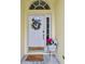 Close-up of the front door with wreath and decorative plants and doormat at 1318 Crimson Clover Ln, Wesley Chapel, FL 33543