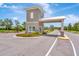 View of community gate house entrance with manicured landscaping on a bright sunny day at 16633 Mooner Plank Cir, Wimauma, FL 33598