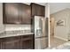 Well-equipped kitchen featuring stainless steel refrigerator, granite countertops, and dark wood cabinetry at 16633 Mooner Plank Cir, Wimauma, FL 33598