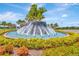 Ornamental water fountain entrance into a community with vibrant landscaping around the circular water feature at 16633 Mooner Plank Cir, Wimauma, FL 33598
