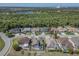 Scenic aerial view of neighborhood homes featuring screened-in pools, near lush, green surroundings and a pond at 2310 Wood Pointe Dr, Holiday, FL 34691