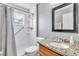 Well-lit bathroom featuring a granite countertop, framed mirror, and a shower with accessibility features at 2310 Wood Pointe Dr, Holiday, FL 34691
