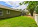 Lush backyard featuring a green lawn, screened-in patio, and partial view of the exterior side of the home at 30623 Bittsbury Ct, Wesley Chapel, FL 33543