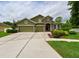 Lovely two-story home with stone detailing, a three-car garage, and meticulously landscaped front yard at 30623 Bittsbury Ct, Wesley Chapel, FL 33543