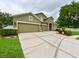 A traditional-style home featuring an attached three-car garage, stone accents, and meticulously landscaped yard at 30623 Bittsbury Ct, Wesley Chapel, FL 33543