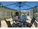 A stylish patio set under a blue umbrella next to a screened-in pool at 30623 Bittsbury Ct, Wesley Chapel, FL 33543