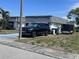 Home exterior featuring a dark colored vehicle parked in the driveway and beautiful Florida foliage at 3542 Delta Pl, Holiday, FL 34691