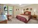 Comfortable bedroom featuring a queen bed, rattan furniture, and bright window views at 4002 Crockers Lake Blvd # 1-128, Sarasota, FL 34238
