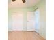 A secondary view of a light-green bedroom with a closet and neutral-toned wood floors at 472 Trout Ln, Oldsmar, FL 34677