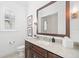 Bright bathroom featuring a wood framed mirror, brown cabinetry, marble countertop, and shuttered window at 5025 W Homer Ave, Tampa, FL 33629