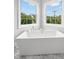 Close-up of a modern white bathtub positioned in front of two bright, sunny windows at 5025 W Homer Ave, Tampa, FL 33629