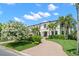 Elegant home featuring a lush front lawn, a brick driveway, and meticulously landscaped gardens at 5025 W Homer Ave, Tampa, FL 33629