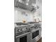 Close up of the Wolf stove with stainless steel hood, white cabinets and light backsplash at 5025 W Homer Ave, Tampa, FL 33629